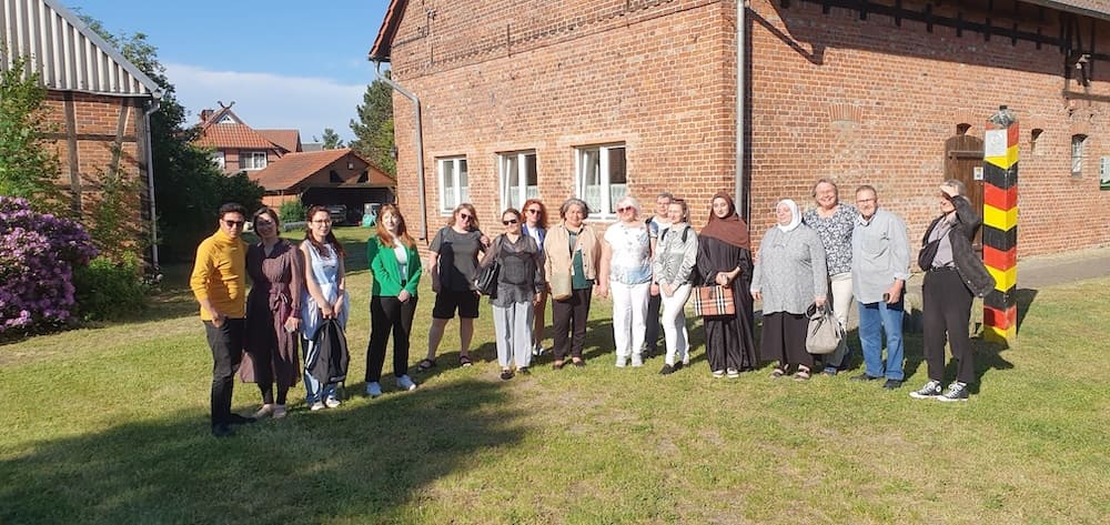 Gruppenfoto vor einem historischen Backsteingebäude während eines gemeinsamen Ausflugs an einem sonnigen Tag.